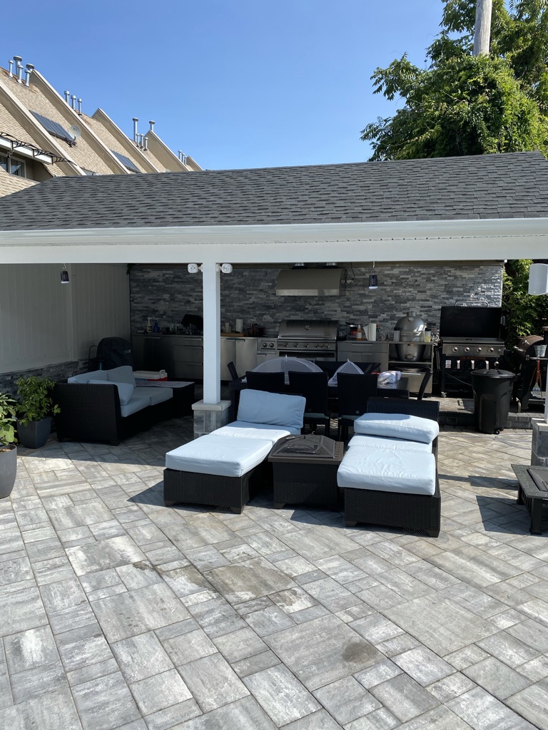 Covered outdoor kitchen with built-in grills and patio lounge seating