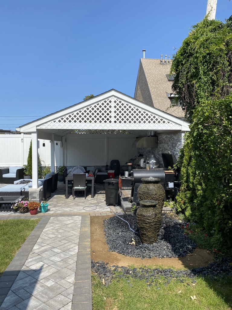 Backyard walkway, stone water fountain, and covered patio pavilion